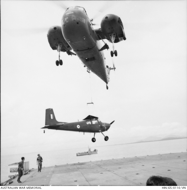 A CH-37 lifts a Cessna 180 from her deck