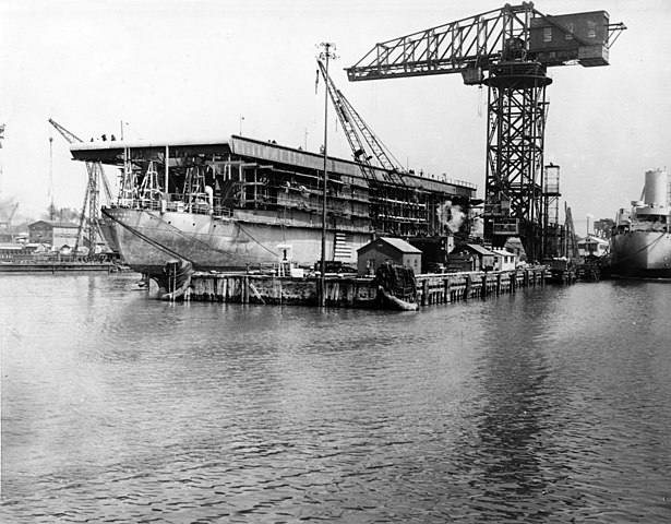 USS Long Island under conversion at Newport News Shipbuilding Virginia 1 April 1941</em></img>“><br></br>
<br></br><em>USS Long Island under conversion at Newport News Shipbuilding Virginia 1 April 1941</em></p>
<p>The hull later used was laid down on 7 July 1939, as the C-3 cargo liner <strong>Mormacmail</strong>, under Maritime Commission contract. She was built by the Sun Shipbuilding and Drydock Company in Chester (Pennsylvania), in Yard No 185. She was launched on 11 January 1940 sponsored by Miss Dian B. Holt. She was in completion when acquired acquired by the Navy on 6 March 1941. She was subsequently converted and later commissioned on 2 June 1941 as USS Long Island, AVG-1; Her first commander was Donald B. Duncan. </p>
<p>Compared to the conversion of Audacity, the one for USS Long Island was much greater in scope, but as amazing as it was, it took less time to perform: The Mormacmail was requisitioned by the US Navy on 6 march 1941 for conversion, and she was completed and commissioned on 2 june 1941, so about four months, for a ship than could carry 21 planes, artillery, a lift, a hangar, and a catapult. So quite more advanced compared to the Audacity, although loosing its merchant payload in the process. The other tradeoff of the design was the absence of an island, corrected on subsequent designs, like the USS Charger. She displaced 11,300 tonnes standard, 14,050 fully loaded, for a length of 141.7 meters at the waterline, 150 meters overall, for 21.2 meters at the waterline and 31.1m overall at deck level, and a draught of 7.66 meters fully loaded.</p>
<p><img decoding=